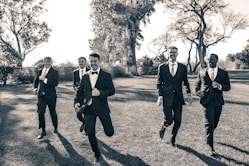 a group of men in suits running across a field