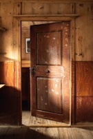 Heavy oak door slightly ajar, revealing a cozy warmly lit interior.