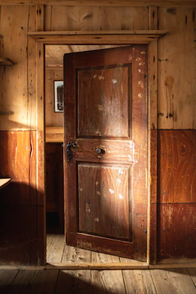 A sleek modern wooden door partially open, revealing a stylish interior with warm lighting.