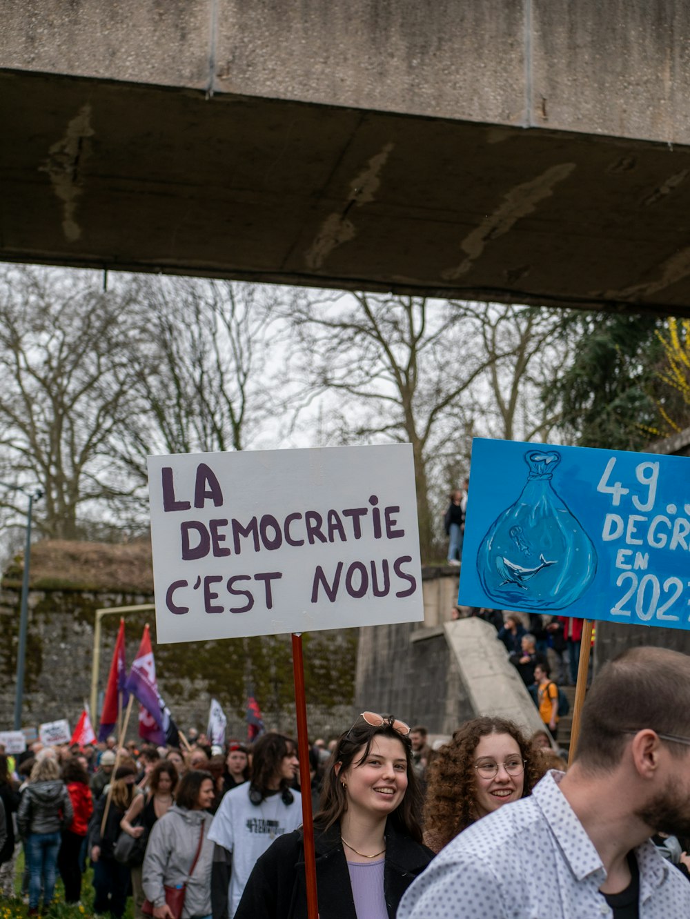 a group of people holding signs in front of a bridge