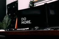 A minimalist workspace with dual monitors showing synchronized data dashboards in dark mode.