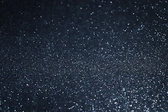 Shimmering silver nuggets scattered on a textured black surface.