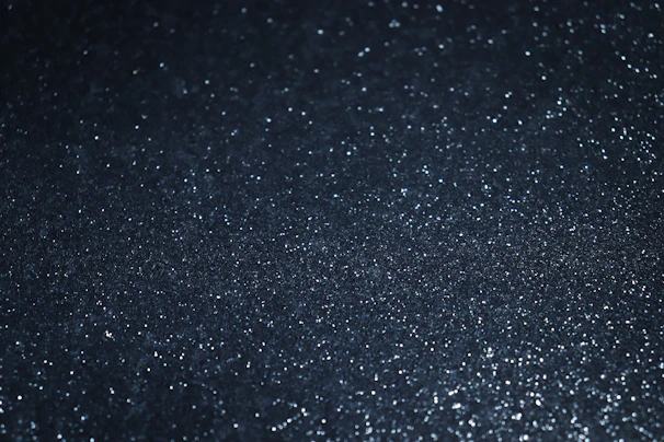 Shimmering silver nuggets scattered on a textured black surface.