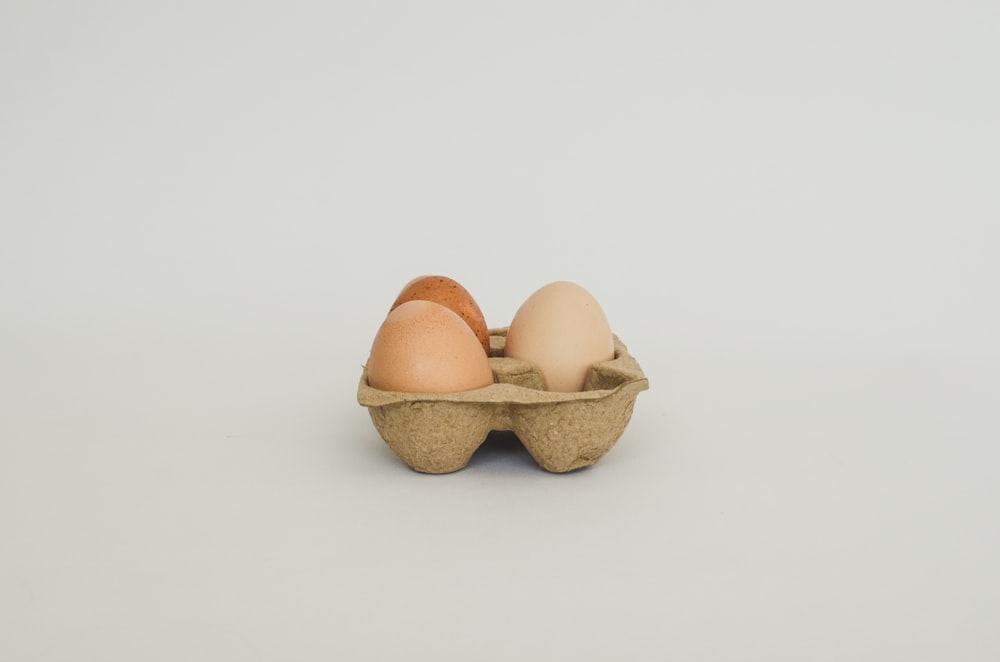 three eggs in a carton on a white background