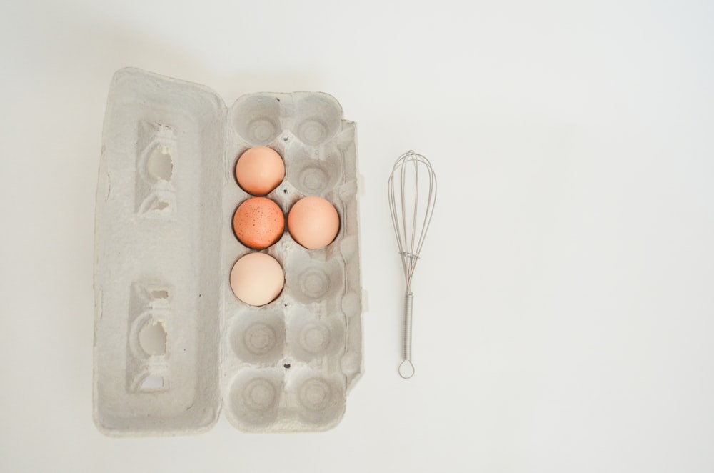 a carton of eggs and a whisk on a table