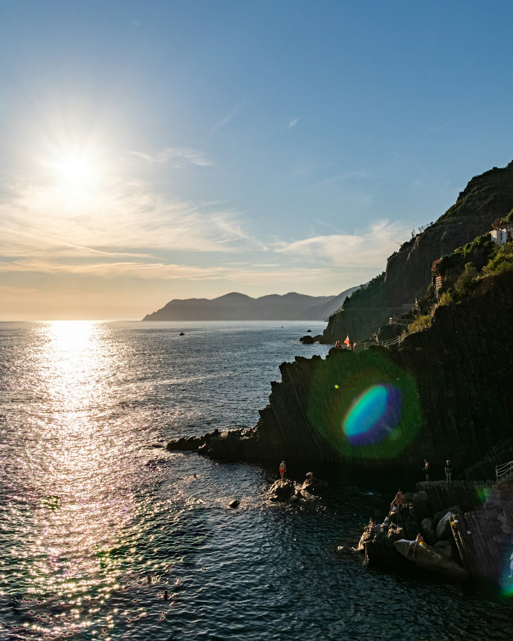 the sun shines brightly over the water near a rocky cliff