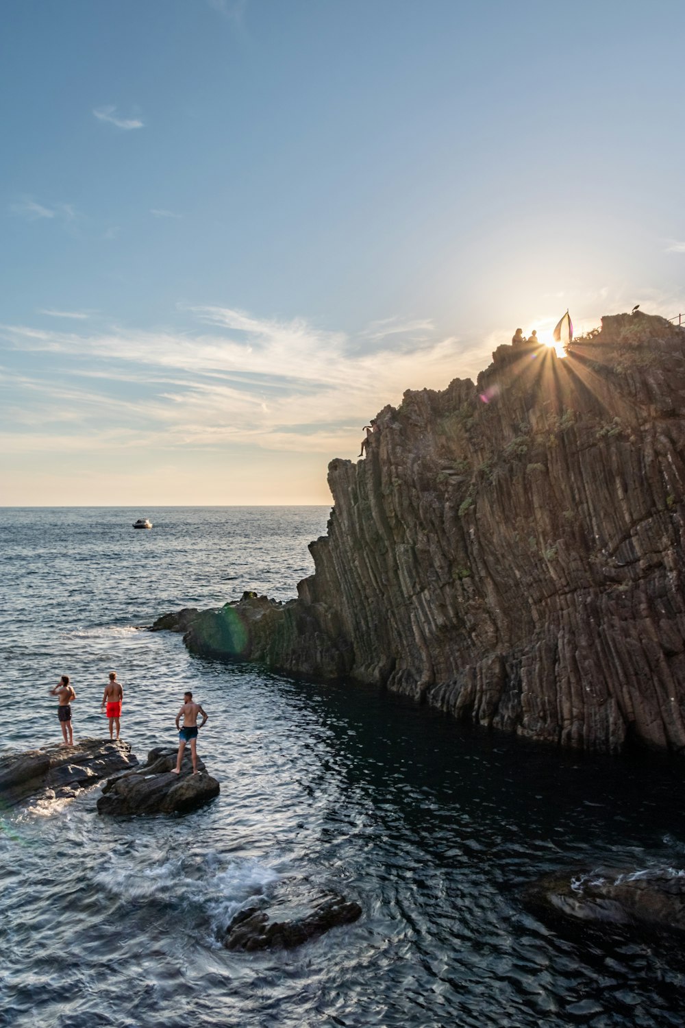 a group of people standing on top of a cliff next to the ocean