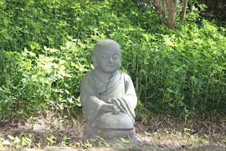 a statue of a buddha sitting in the grass