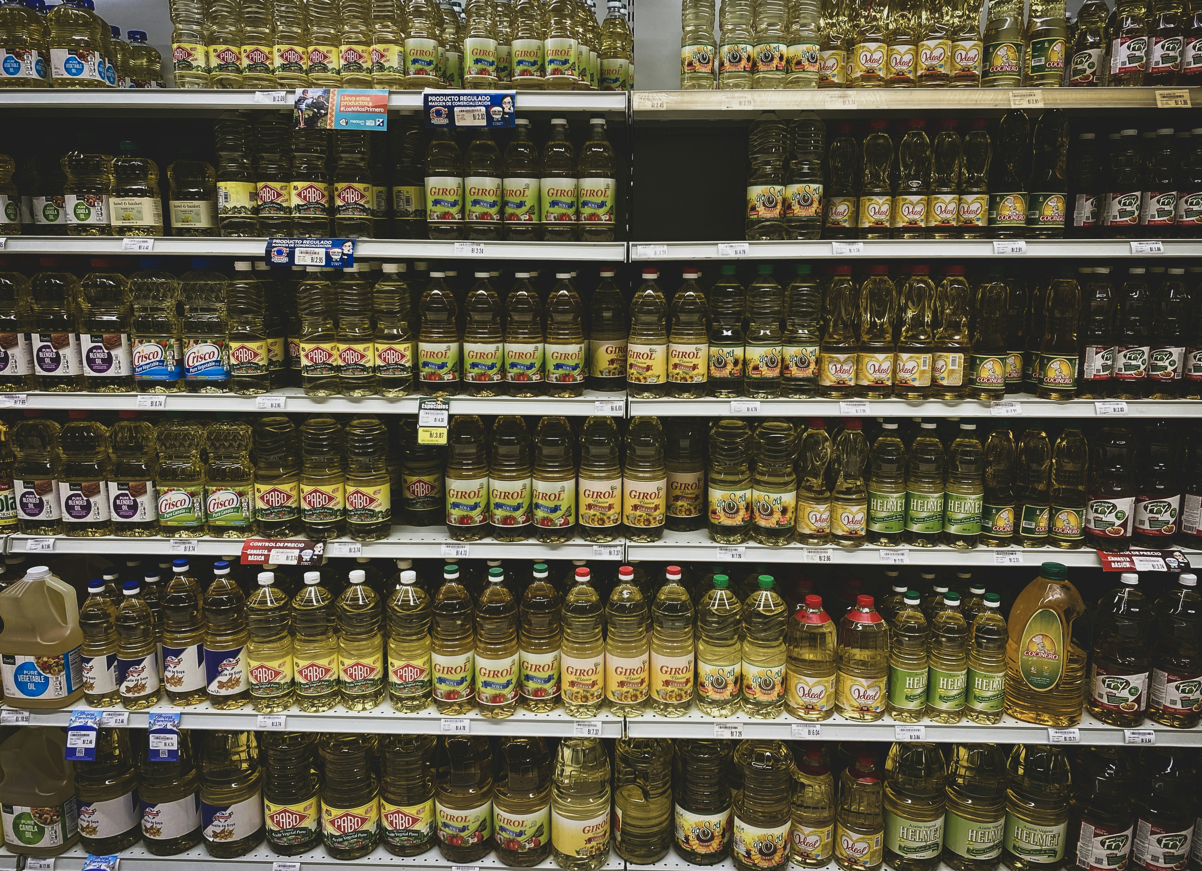 Various cooking oil bottles on market shelf showing global supply diversity