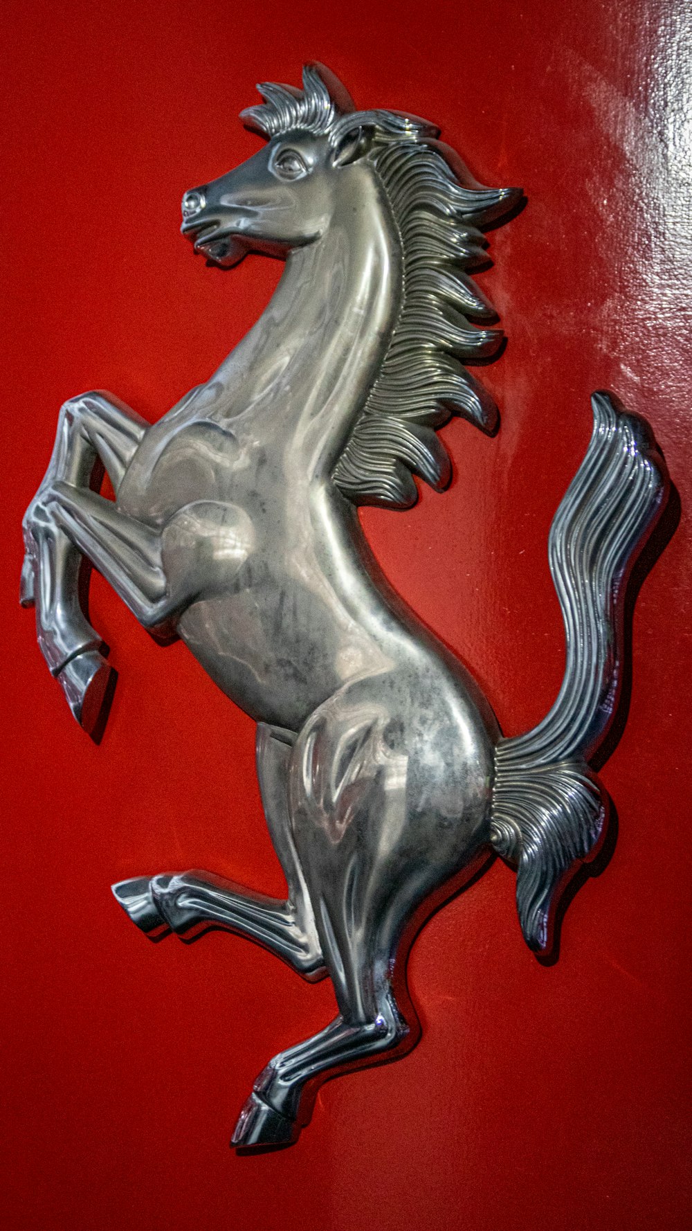 Un emblema de caballo plateado en una pared roja