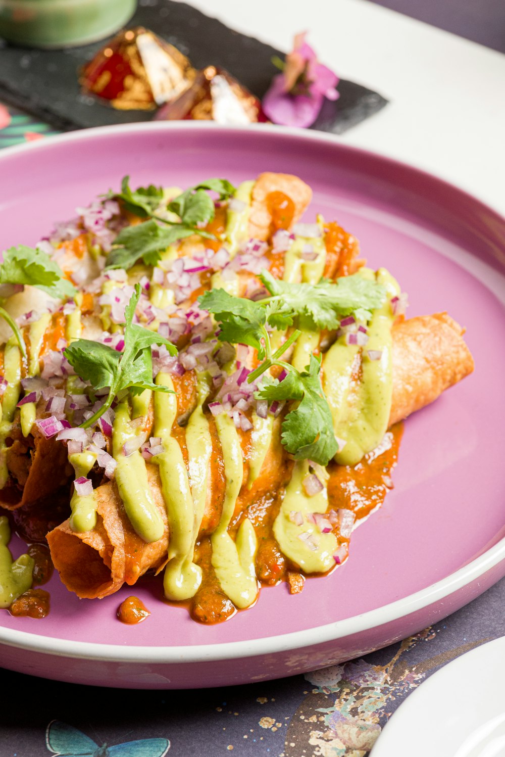 Un plato rosa cubierto con comida encima de una mesa