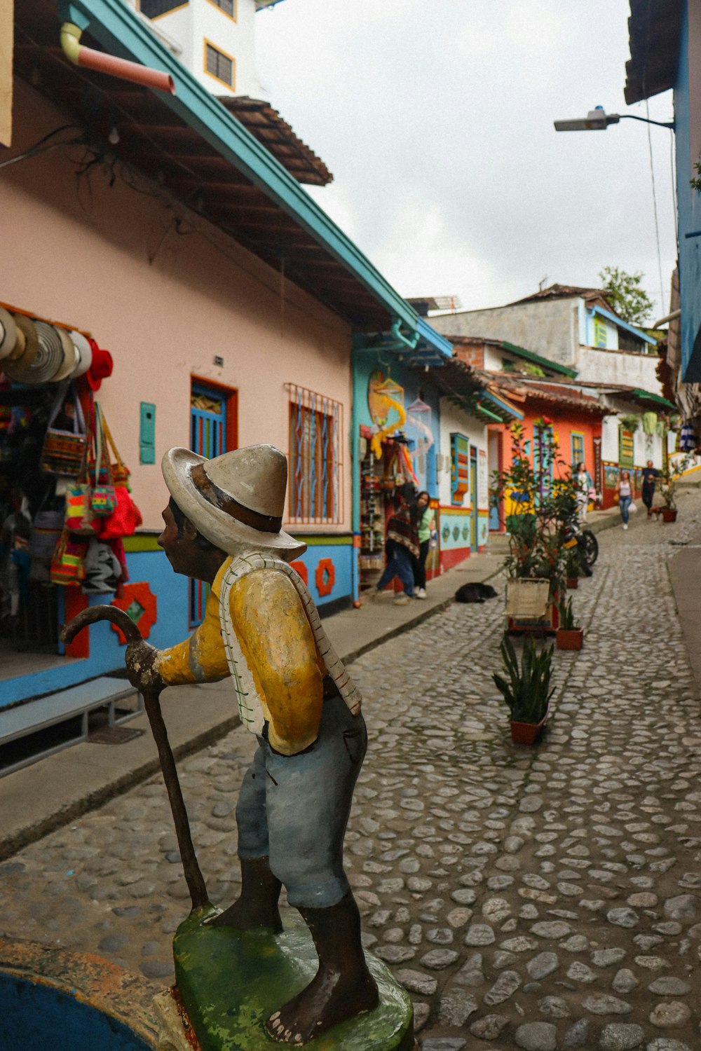 Una estatua de un hombre sosteniendo un palo en una calle empedrada