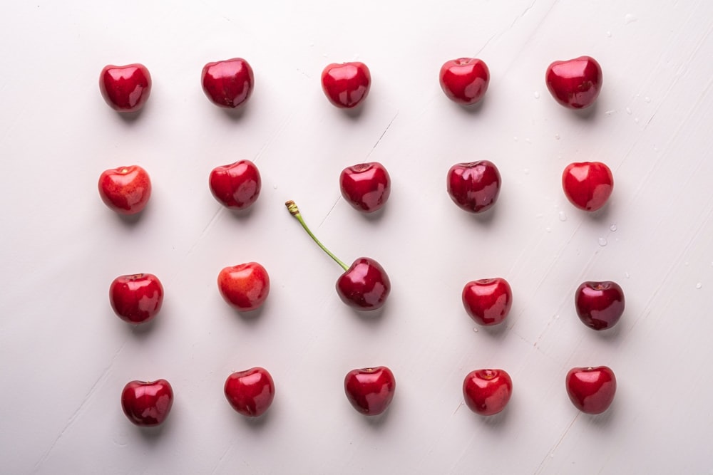 Un grupo de cerezas rojas sobre una superficie blanca