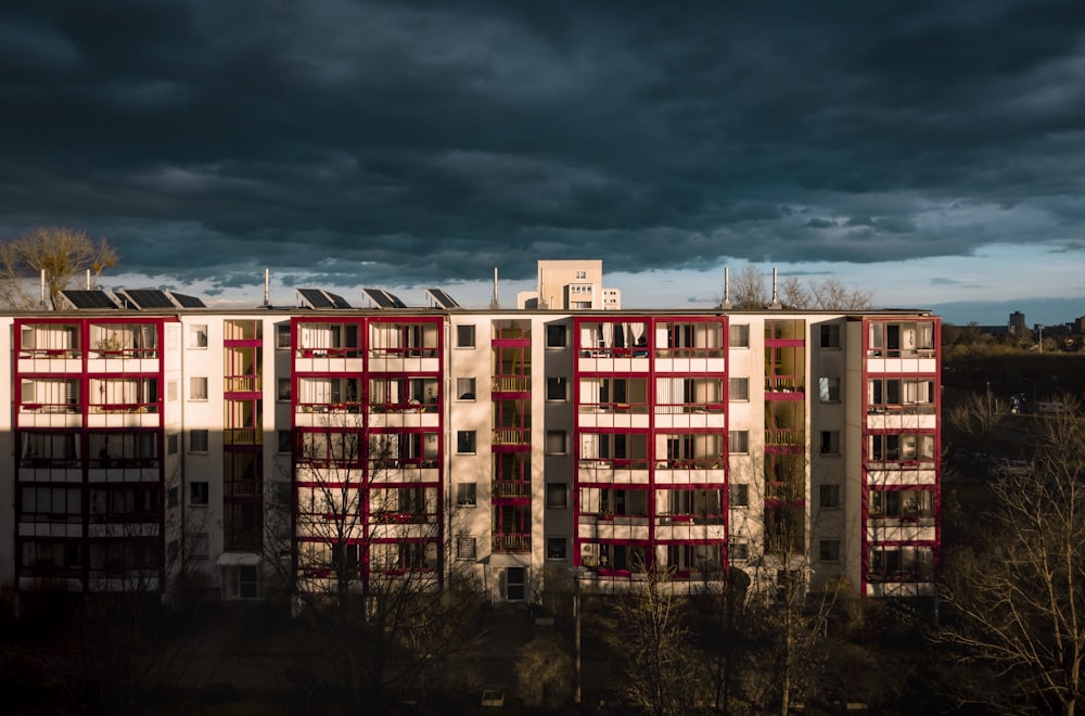 a tall building with red and white windows under a cloudy sky