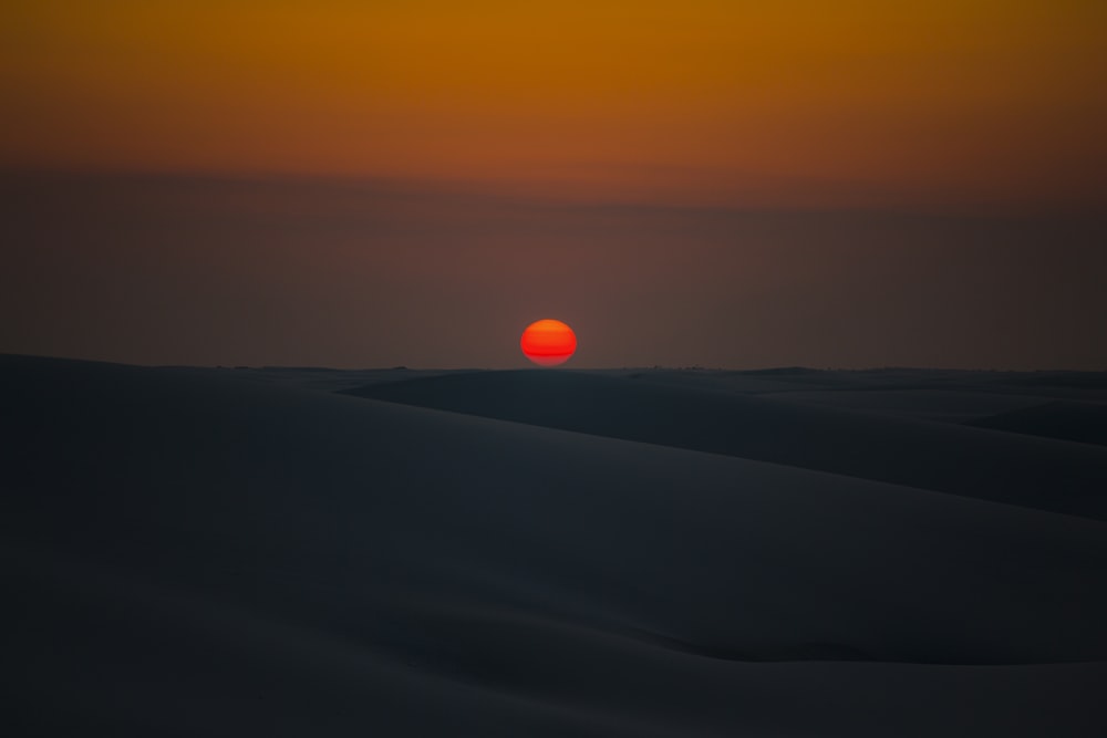 the sun is setting over the horizon of the desert