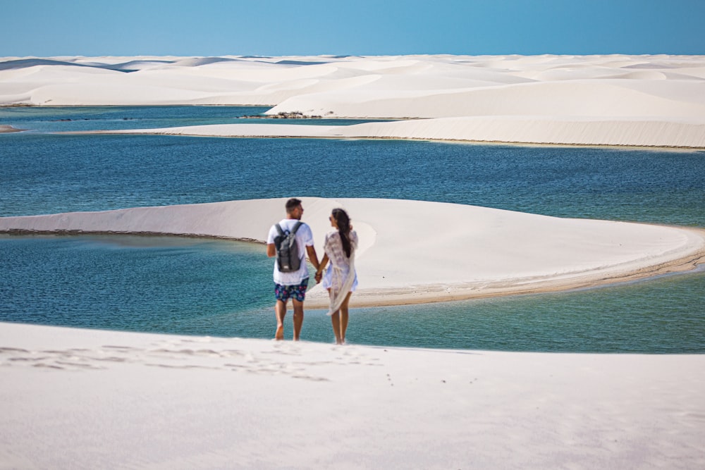 Un hombre y una mujer parados en la cima de una playa de arena