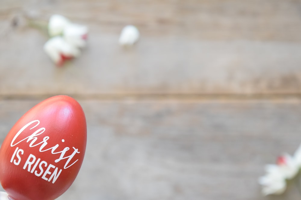 a hand holding a red painted egg with the words cherry is risen written on it