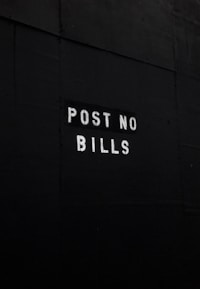 A dark surface features the text 'POST NO BILLS' stenciled in white letters, conveying a clear instruction against placing advertisements or posters.