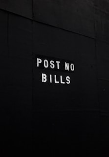 A dark surface features the text 'POST NO BILLS' stenciled in white letters, conveying a clear instruction against placing advertisements or posters.