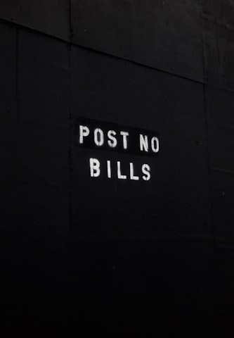 A dark surface features the text 'POST NO BILLS' stenciled in white letters, conveying a clear instruction against placing advertisements or posters.