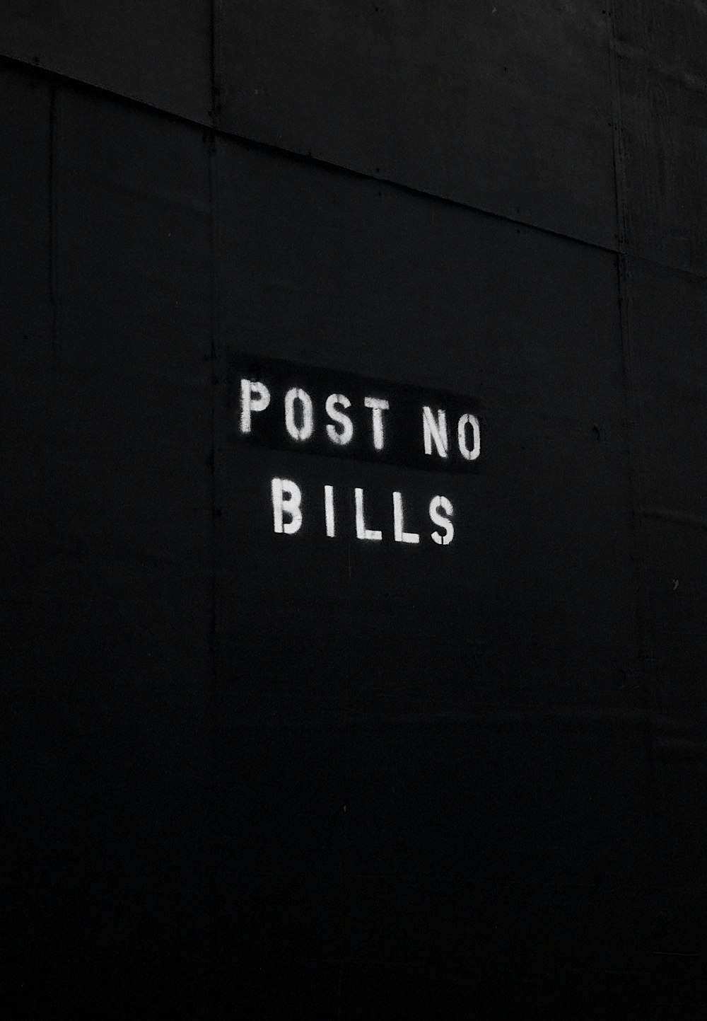 a sign that reads post no bills on a black wall