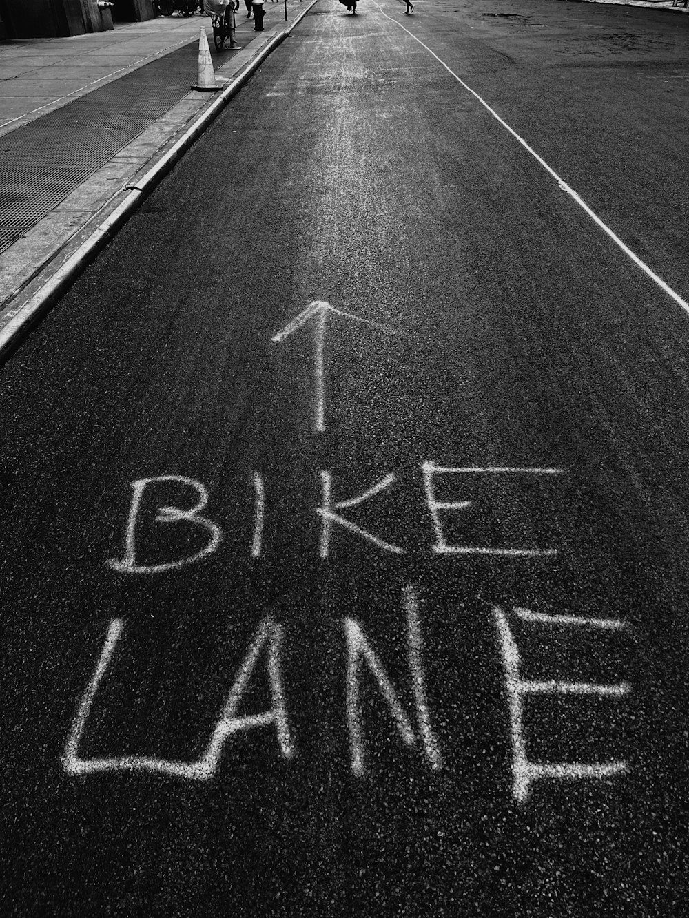 a black and white photo of a street with the words bike lane written in chalk