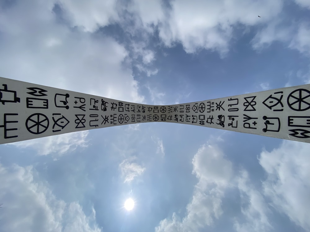 two white signs with black writing on them in front of a cloudy sky