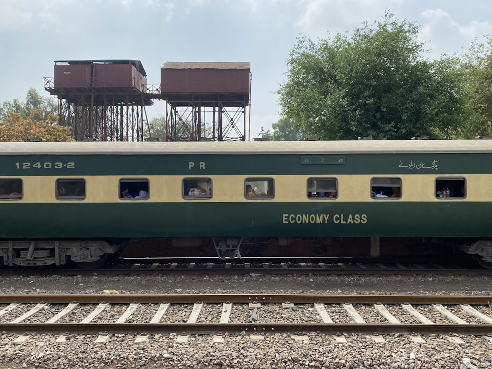 a green and yellow train traveling past a water tower