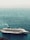 A large cruise ship is docked at a port, with calm ocean waters in the background. The vessel has a white hull adorned with colorful designs and features multiple decks with visible windows. Smoke is gently billowing from the smokestack, indicating that the ship might be preparing to set sail.