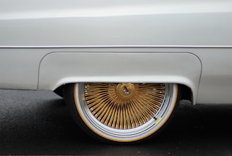 Close-up of a high-end car's polished gold-accented wheel spinning on a racetrack.