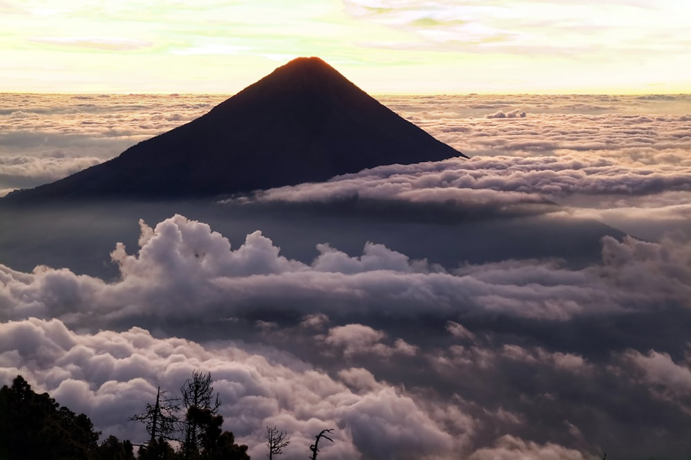 a mountain surrounded by clouds in the sky