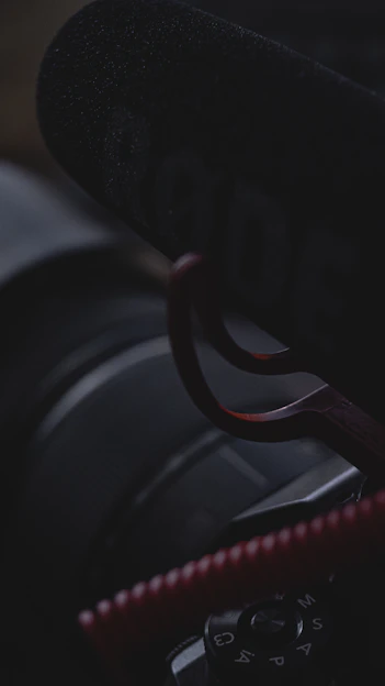 A moody, gold-toned photograph of a camera and microphone set against a dark background, reflecting the contemplative vibe of the brand.