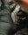 A person wearing black gloves is holding a tattoo machine close to a surface, possibly human skin, with visible tattoo patterns and ink.