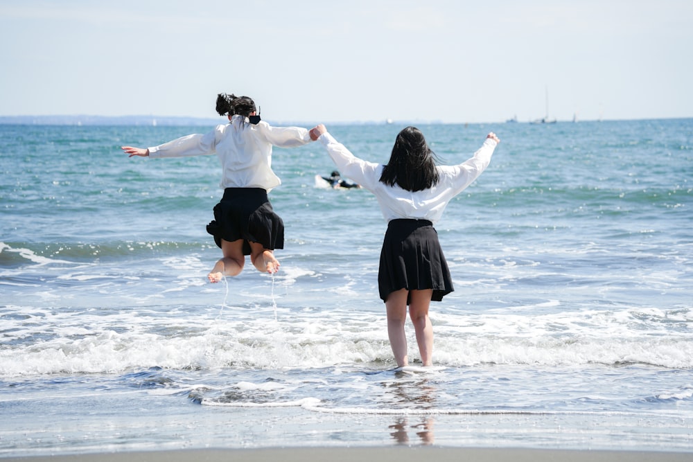 two women jumping in the air at the beach