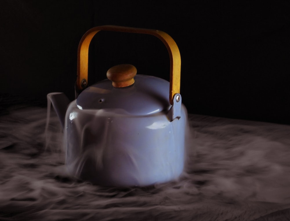 a tea kettle with a wooden handle on a table