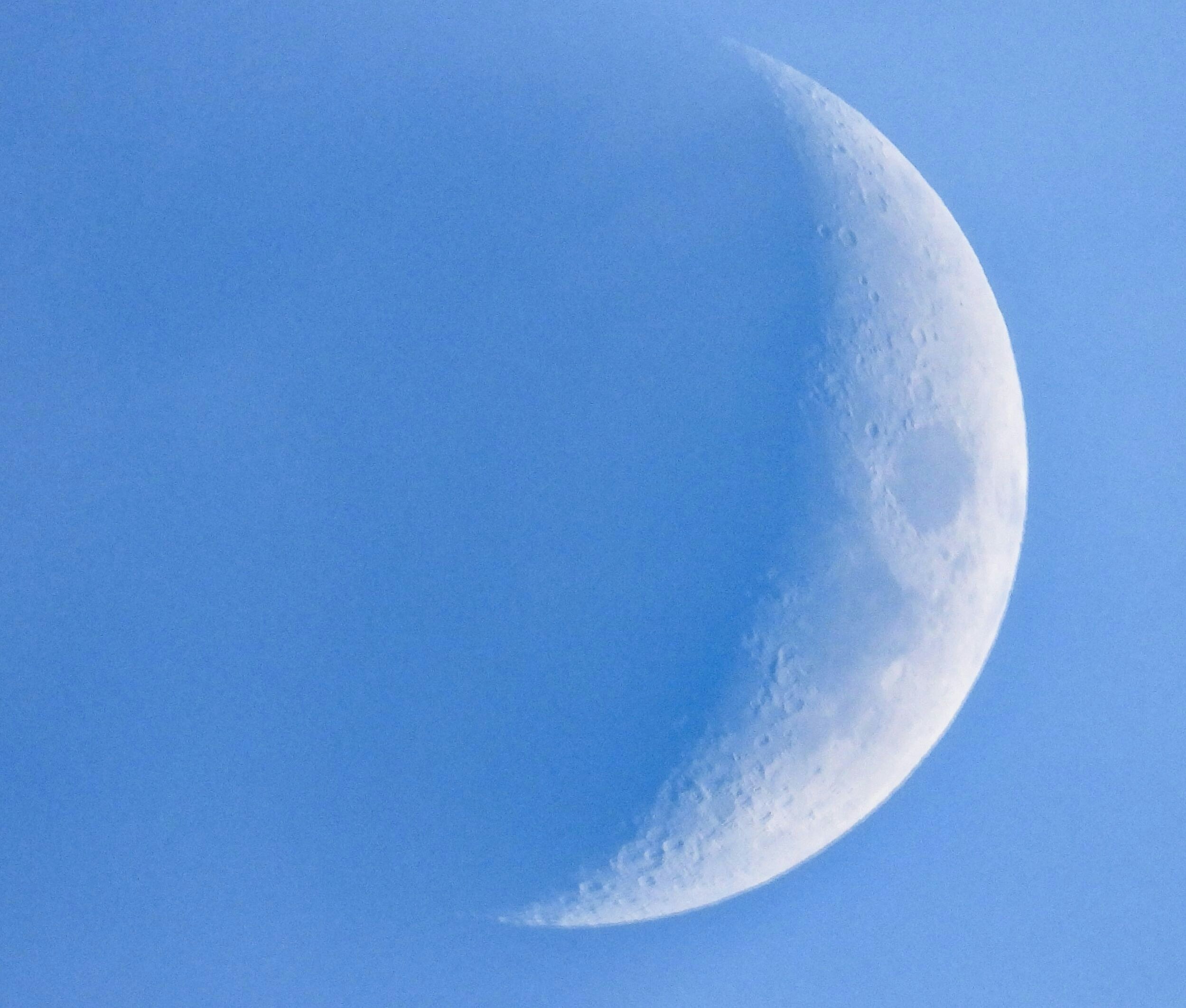 a half moon in a clear blue sky