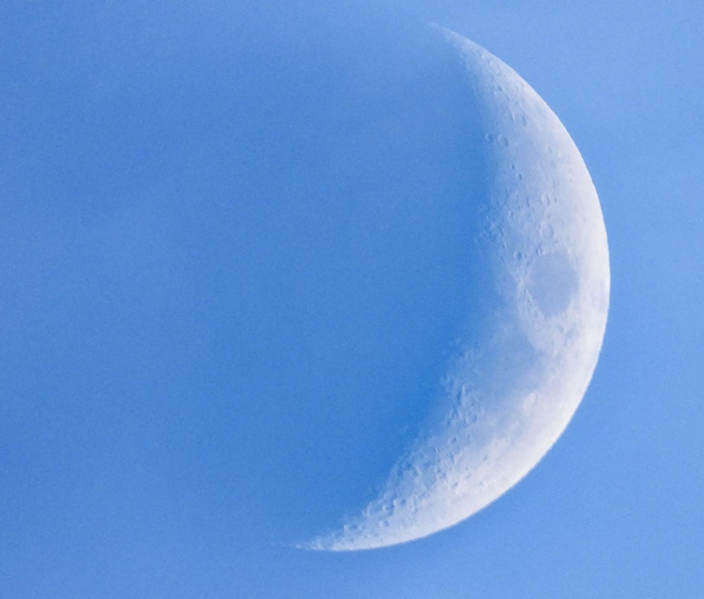 a half moon in a clear blue sky