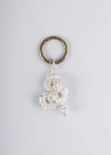 A whimsical keychain featuring a tiny book and floral charms inspired by Raven T. Pendragon’s art.