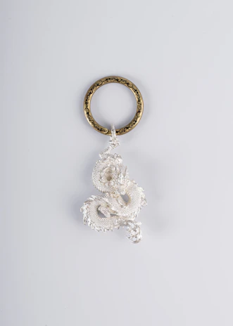 A whimsical keychain featuring a tiny book and floral charms inspired by Raven T. Pendragon’s art.