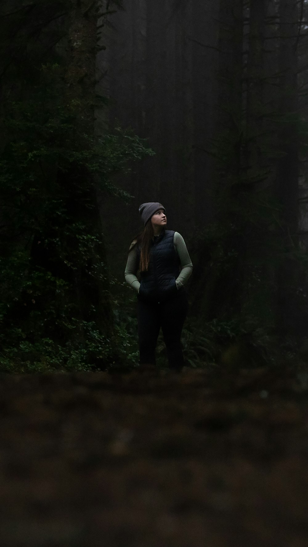 a woman standing in the middle of a forest