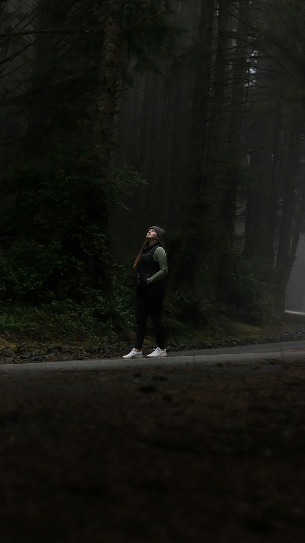 a man standing on the side of a road next to a forest