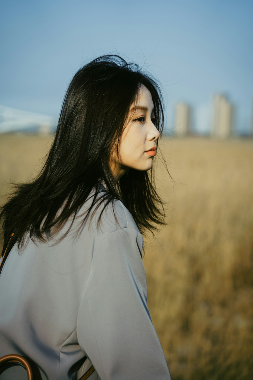 a woman with long hair standing in a field