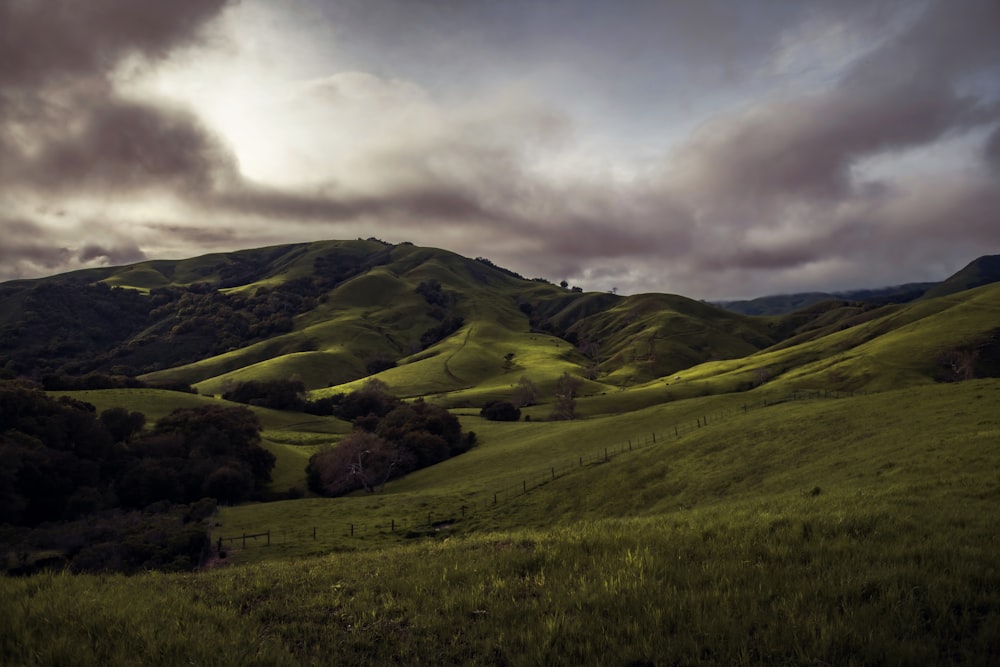 a lush green hillside under a cloudy sky