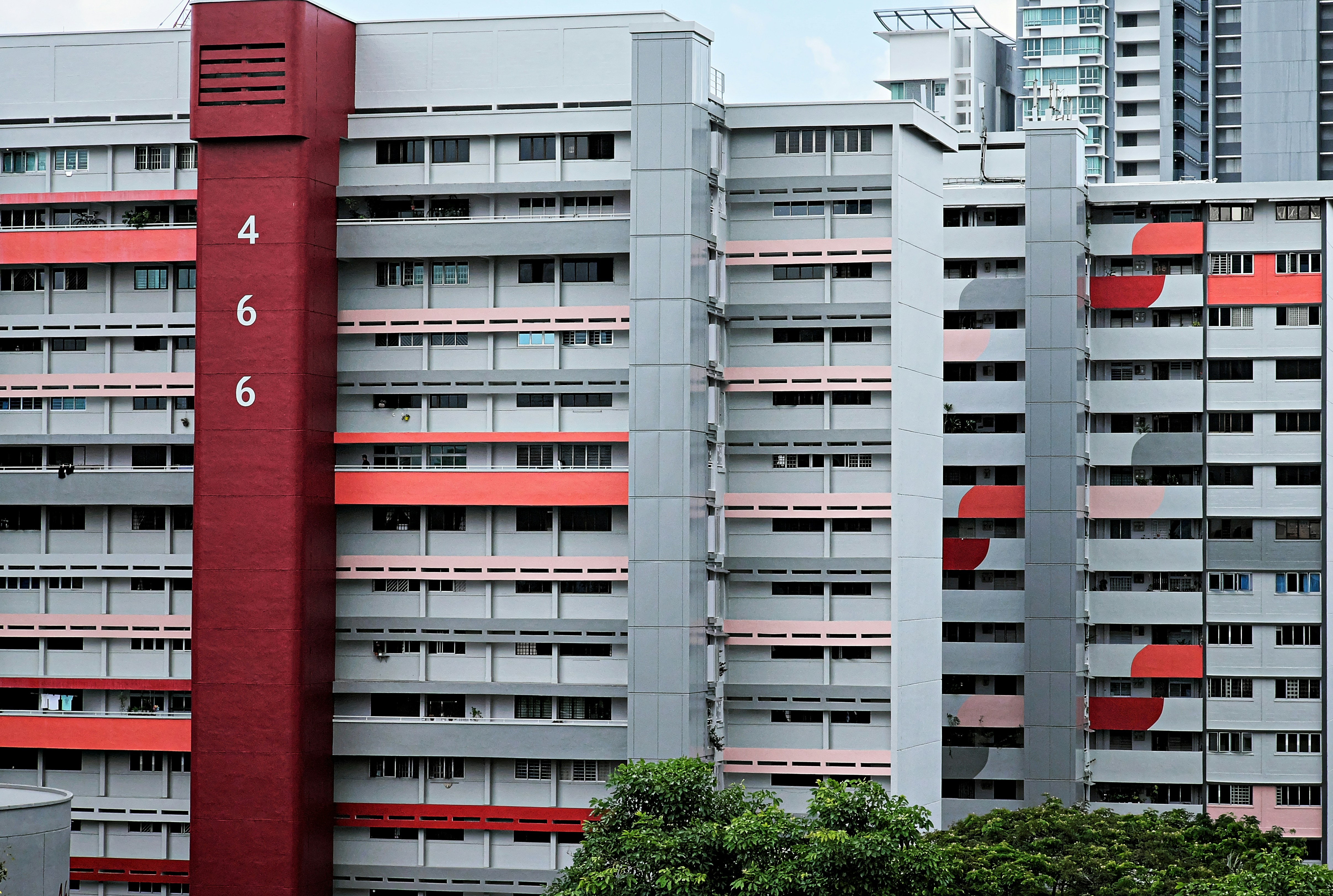 a tall red and grey building next to trees