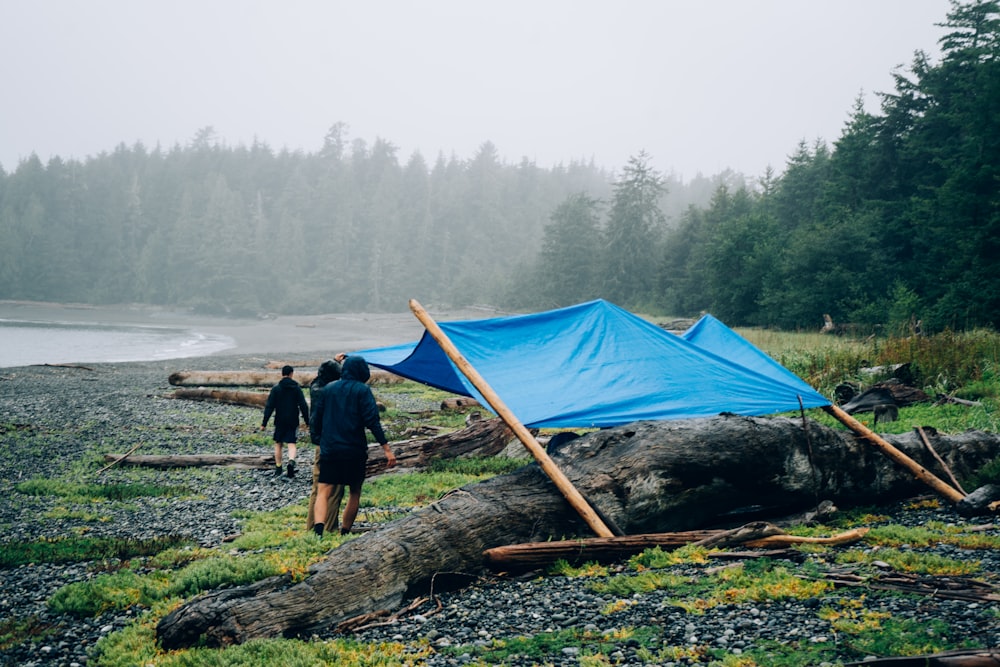 a couple of people standing next to a blue tarp