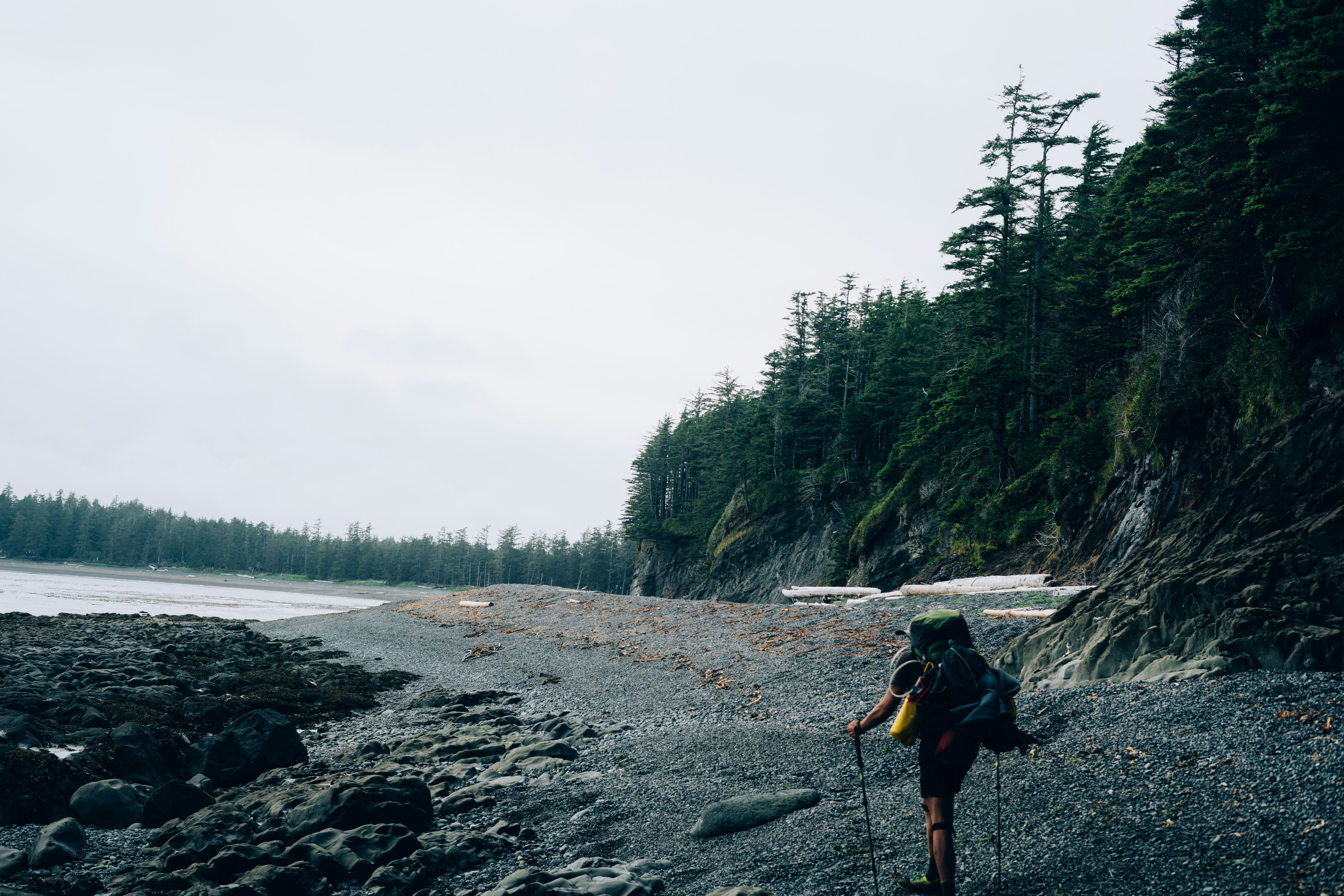a person with a backpack walking on a rocky beach
