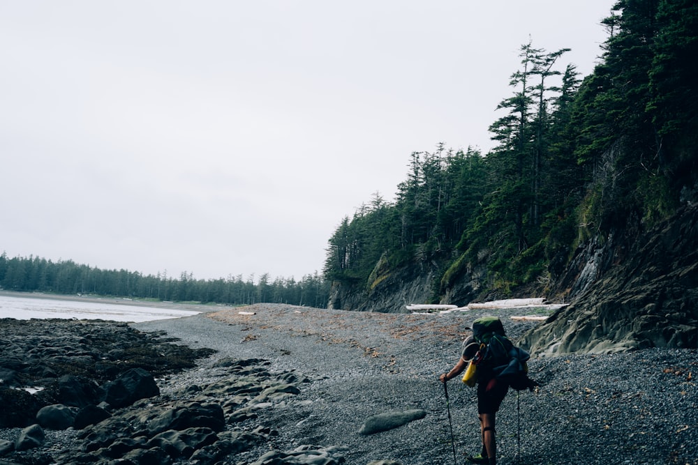 a person with a backpack walking on a rocky beach