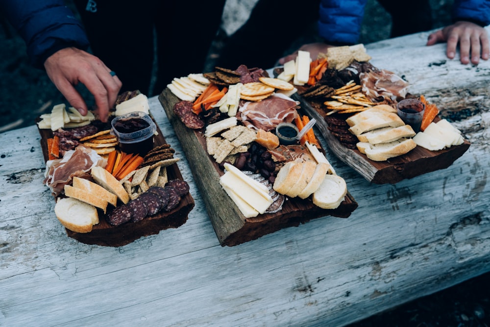 a couple of trays of food sitting on top of a wooden table