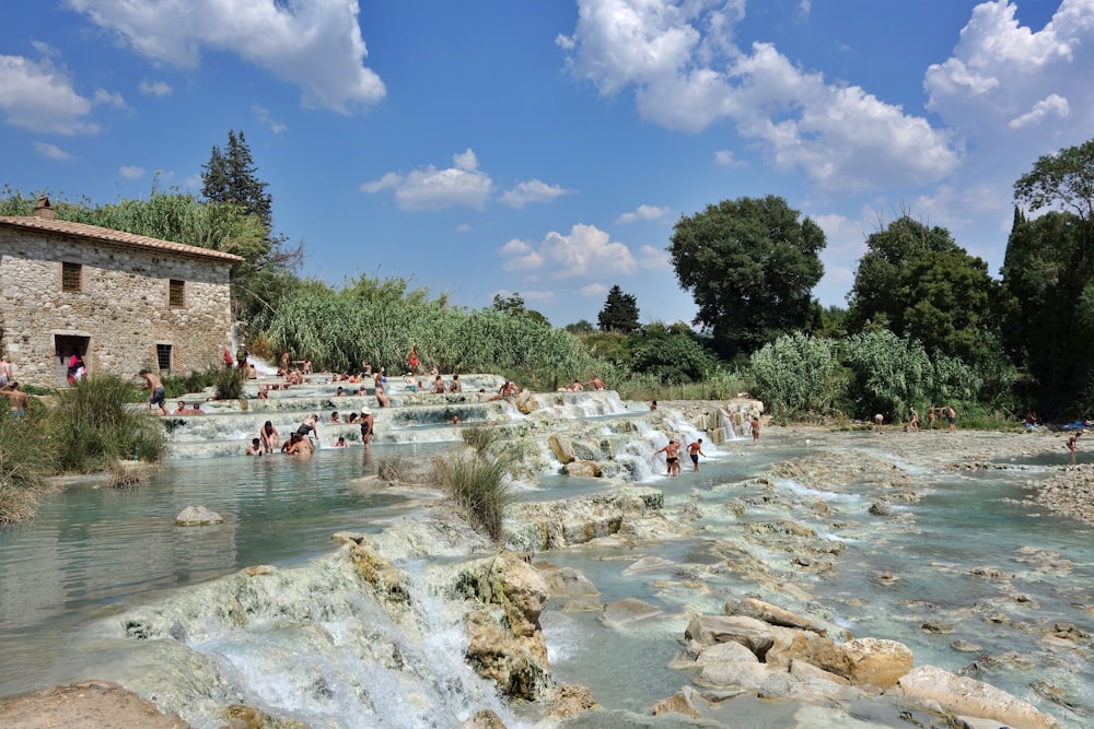 a group of people swimming in a river next to a stone building