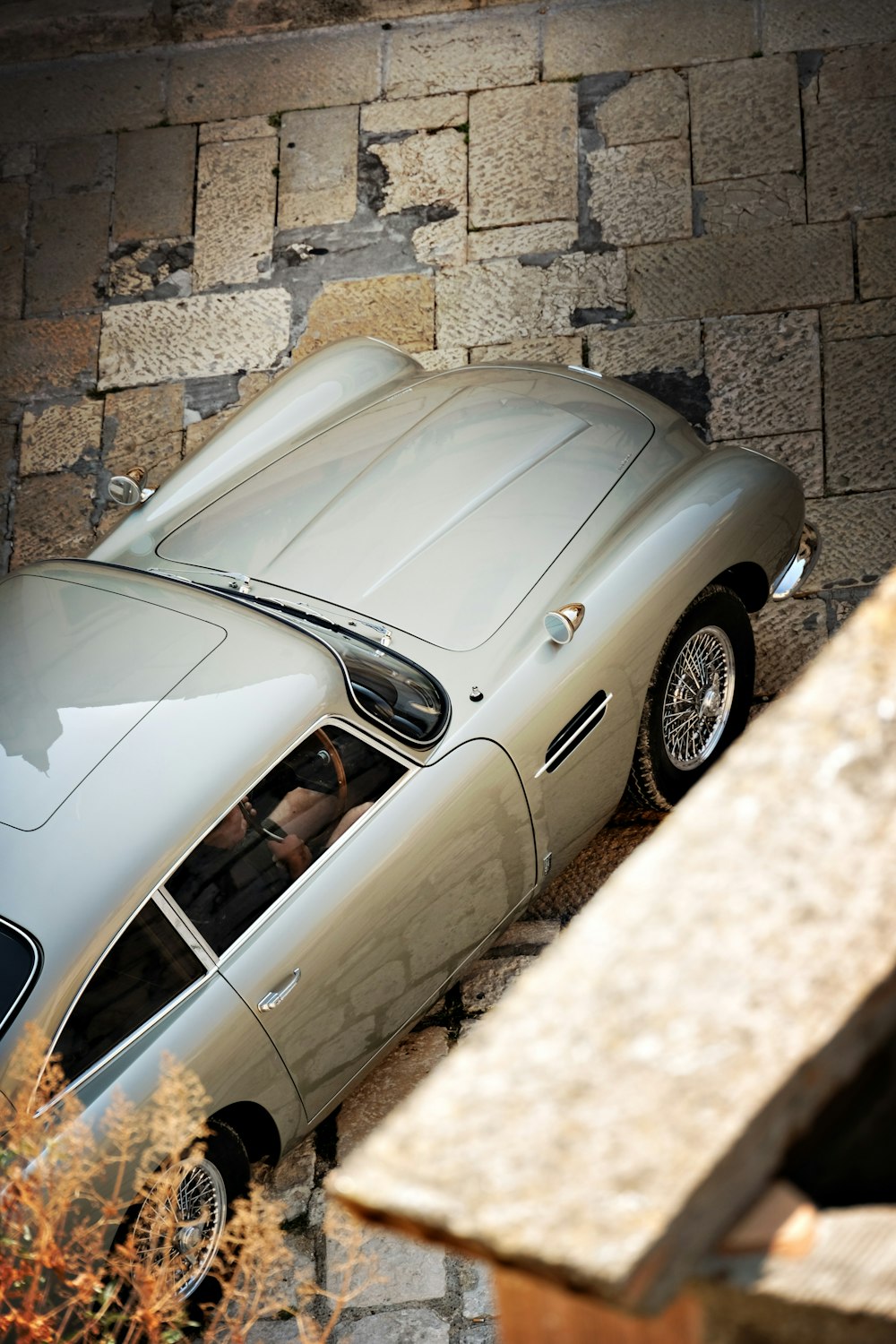 a silver sports car parked in front of a brick wall